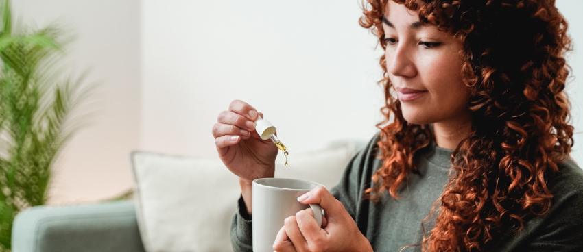 Young woman adding HeyerPower Wellness CBD oil to her drink